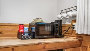 A kitchenette with a microwave, coffee creamer, and a carton of milk on a wooden counter. - Room 17 – Queen Beds (Lead)