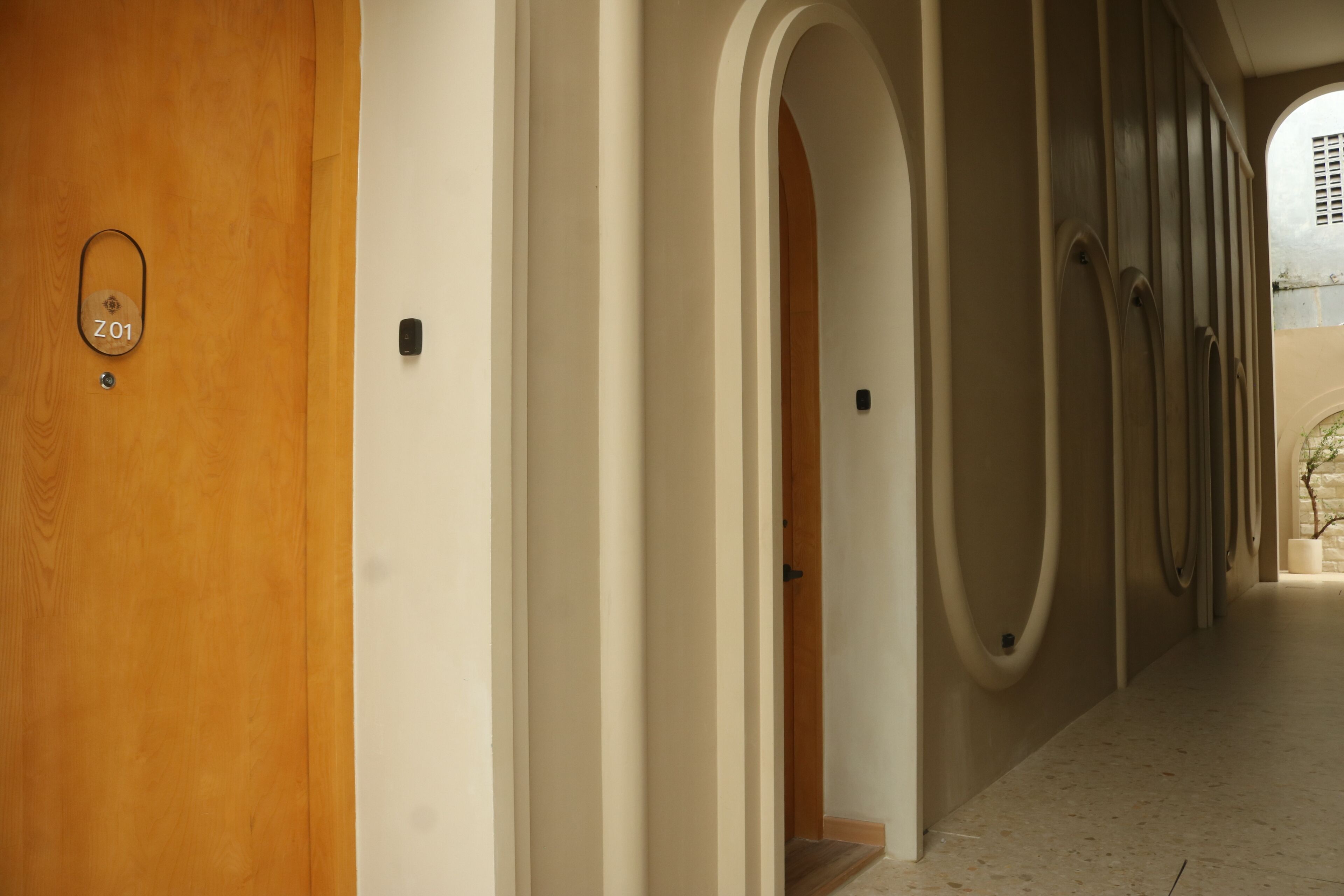 A corridor with a wooden door labeled "Z01", a white wall, and a series of arches.