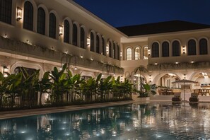 Une piscine intérieure dont l’eau reflète l’architecture du bâtiment, entourée d’une végétation luxuriante et agrémentée d’espaces de détente.