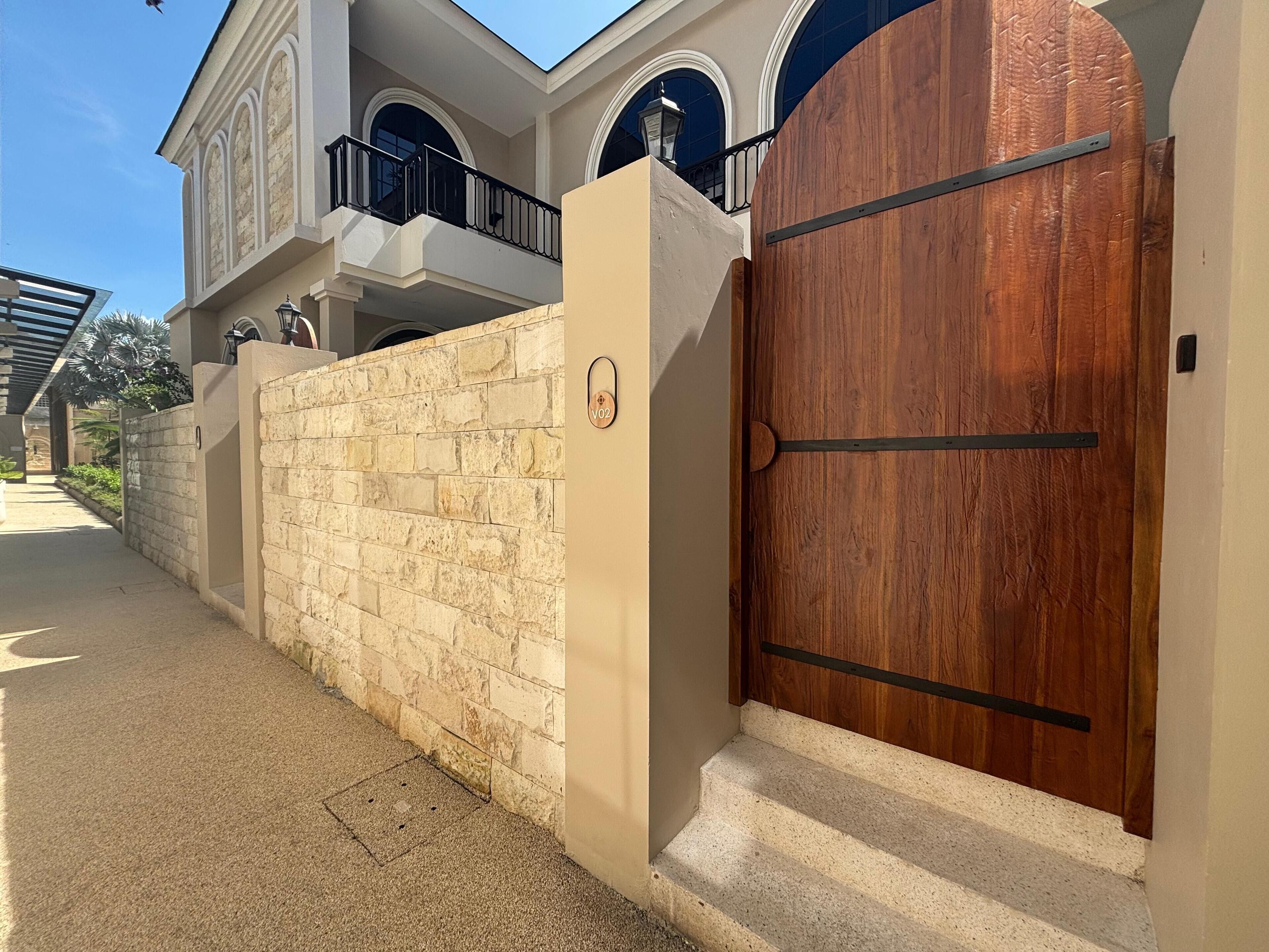 A gated entrance with a stone wall and a wooden door.