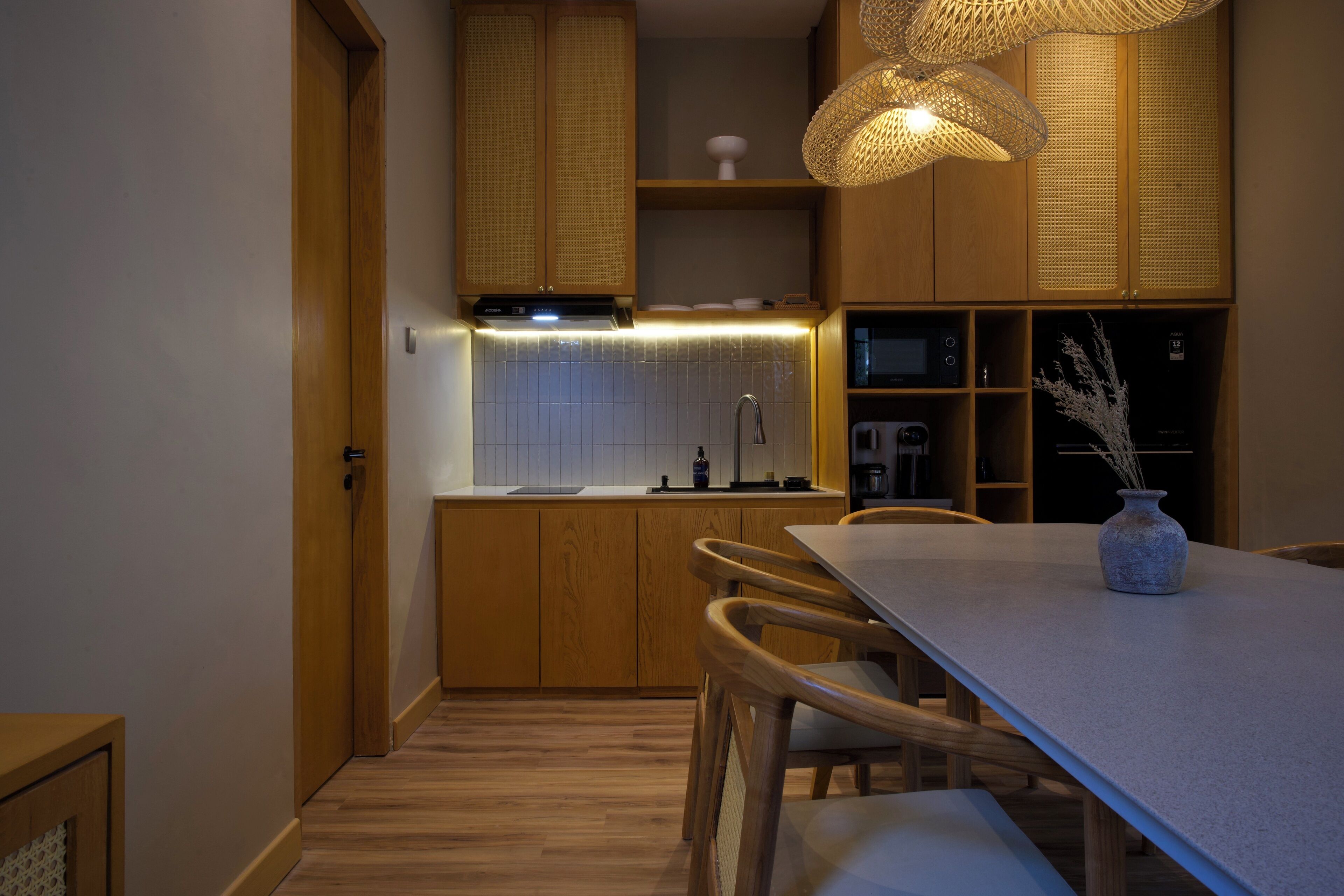 Una cocina moderna con armarios de madera, microondas integrado y comedor con mesa y sillas.