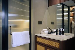 Un baño moderno con un espejo grande, lavamanos blanco y toallero.