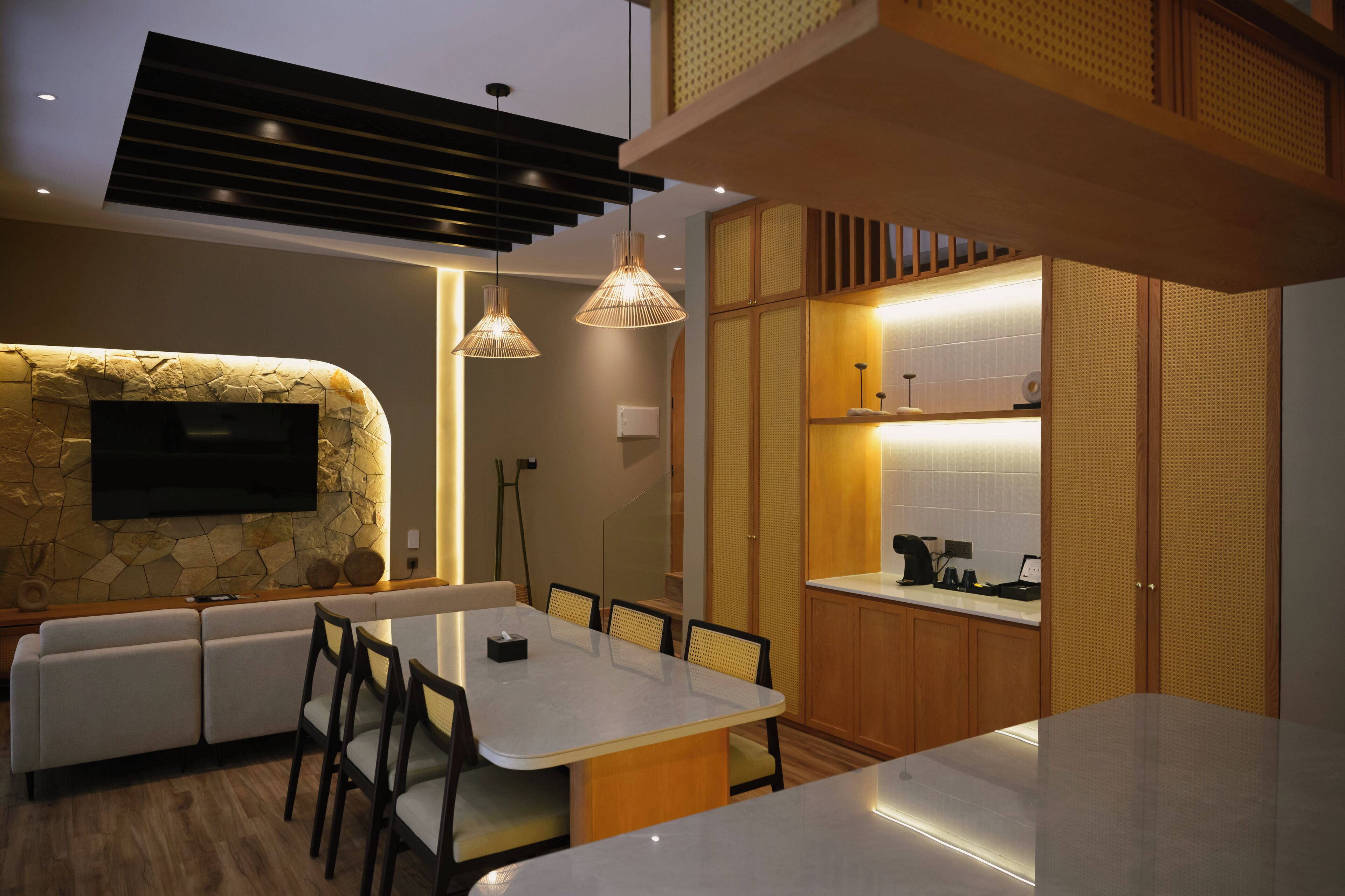Una cocina moderna con una pared de acento de piedra, televisor integrado e iluminación colgante.