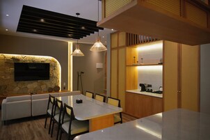Cozinha moderna com parede em pedra decorativa, TV integrada e iluminação pendente.