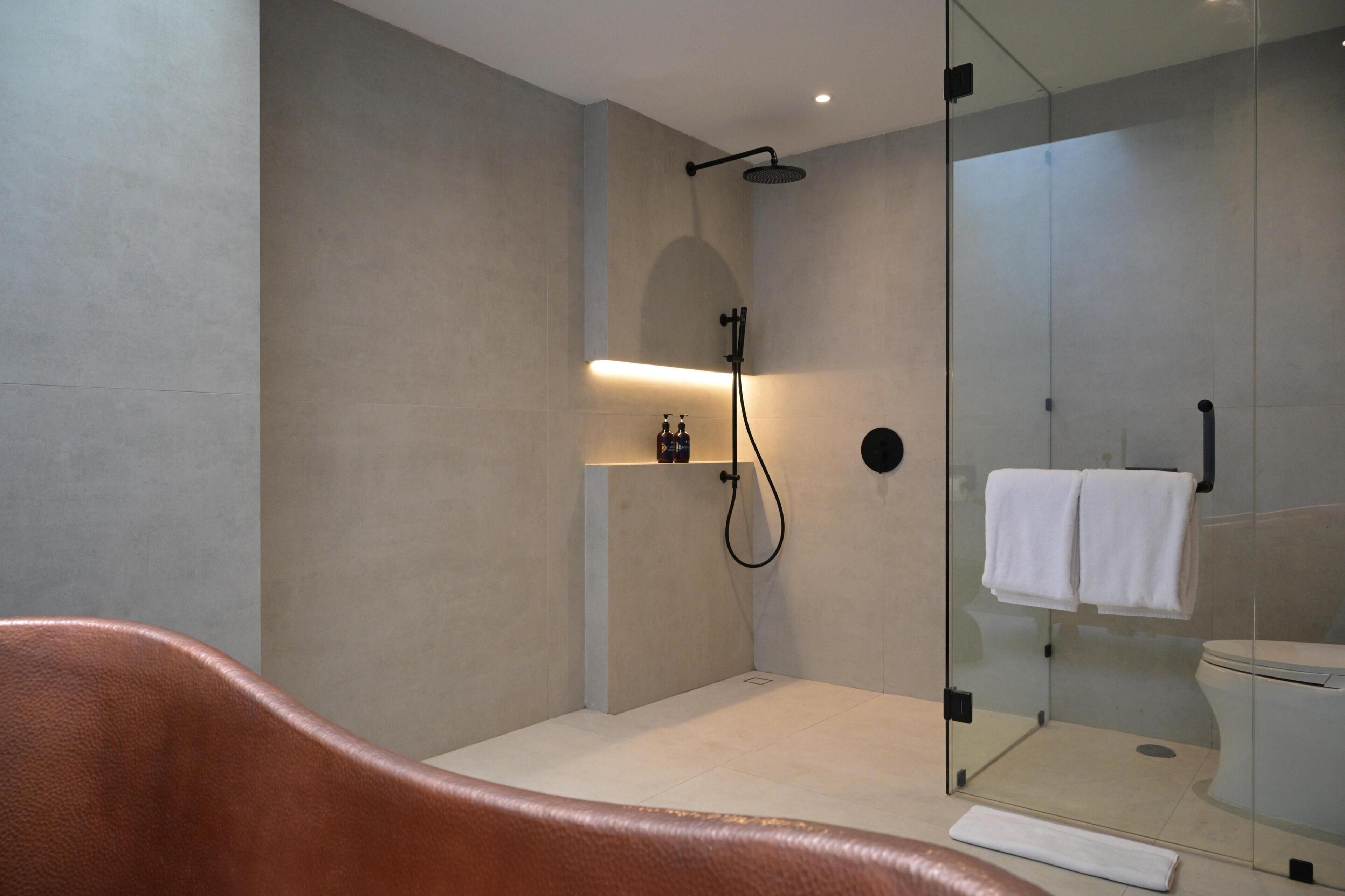 Ein modernes Badezimmer mit einer Duschkabine, einer Toilette und einem integrierten Ablagefach mit Pflegeprodukten.