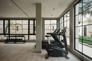 A gym with exercise equipment, large windows, and a view of the outside.