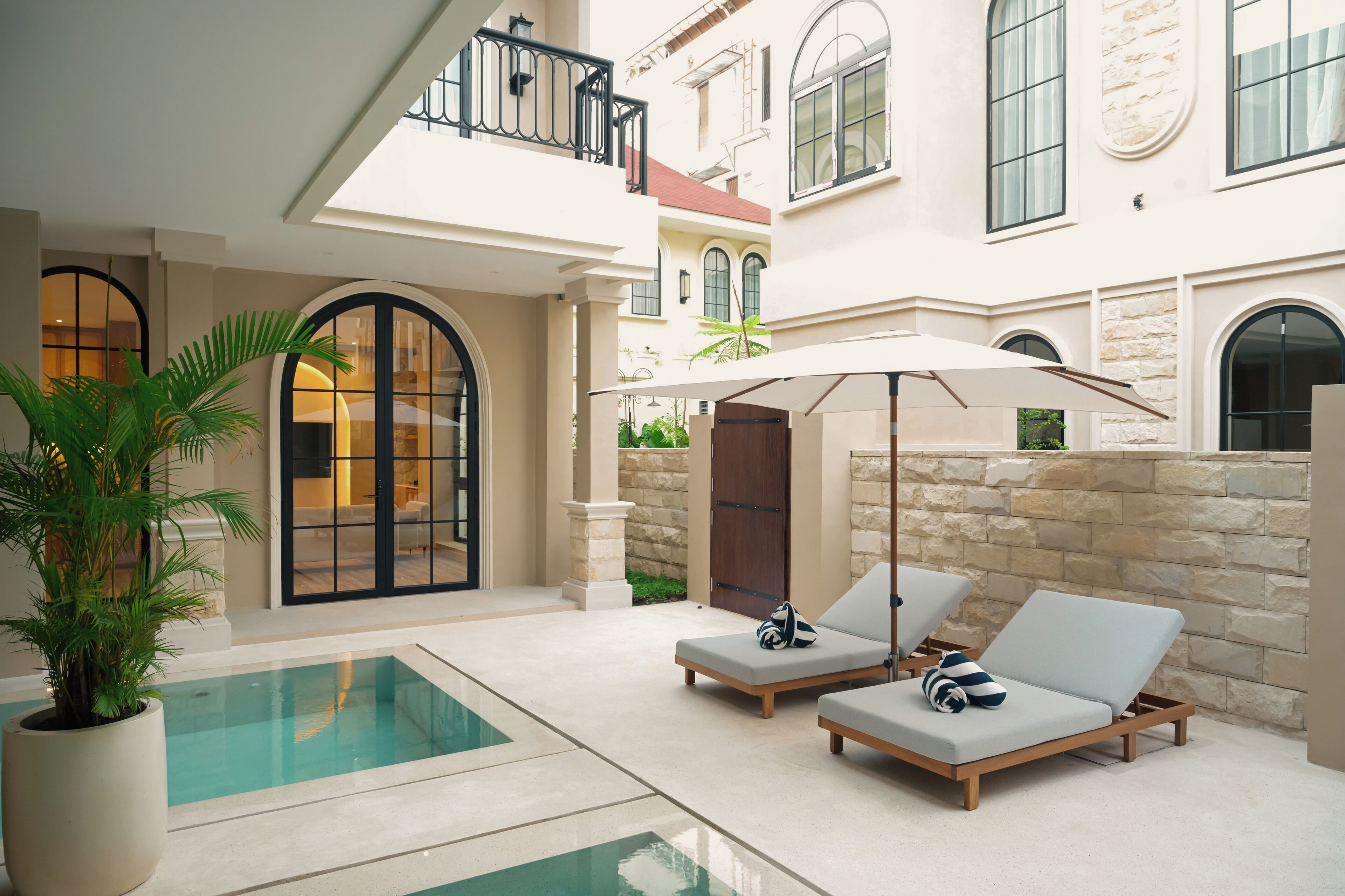 A pool area with lounge chairs and a potted plant.