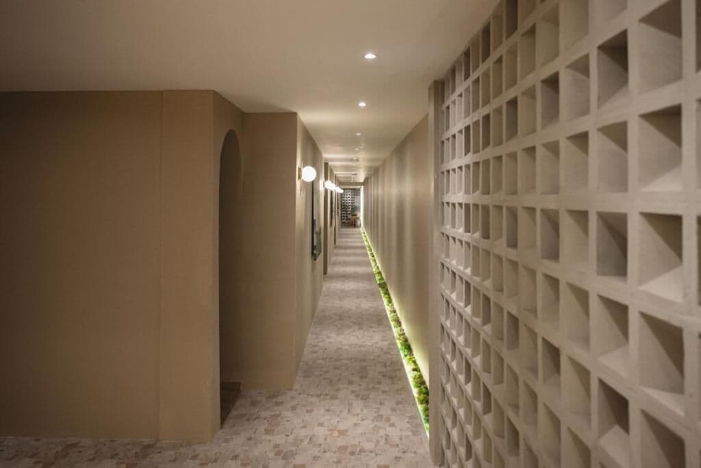 Ein Flur mit einem gemusterten Boden, einer Wand mit geometrischem Dekor und Einbauleuchten.