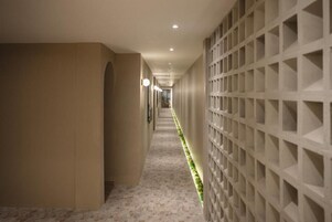 A hallway with a patterned floor, a wall with a geometric design, and recessed lighting.