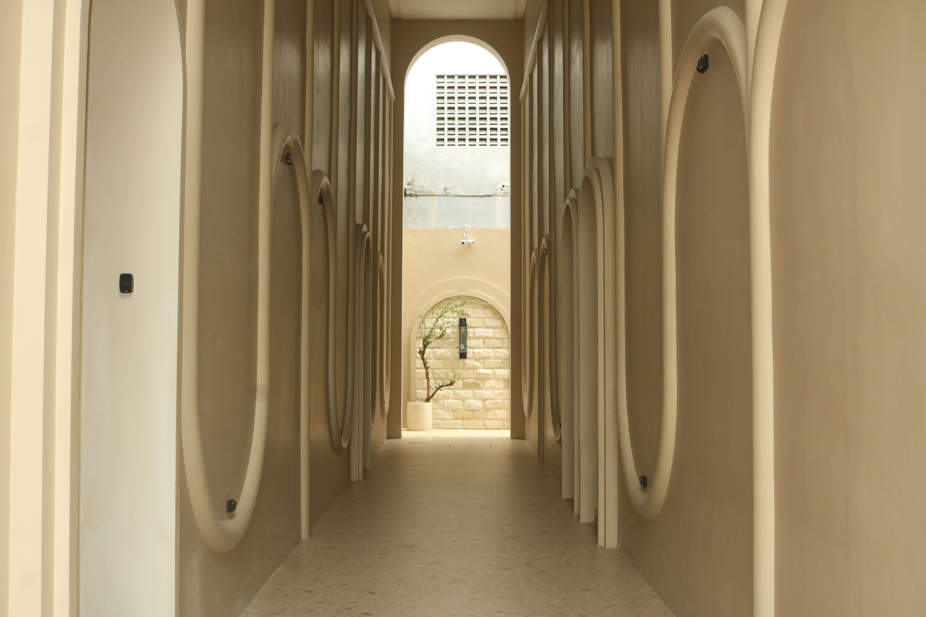 Un corridoio con porte ad arco e un muro in pietra alla fine.