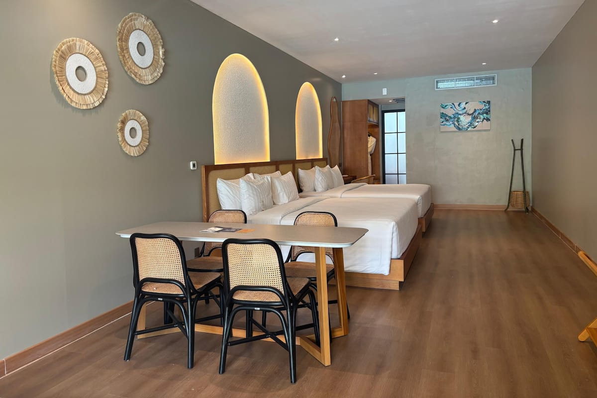Une chambre d’hôtel avec un grand lit, une table à manger avec des chaises et une vue sur l’extérieur.
