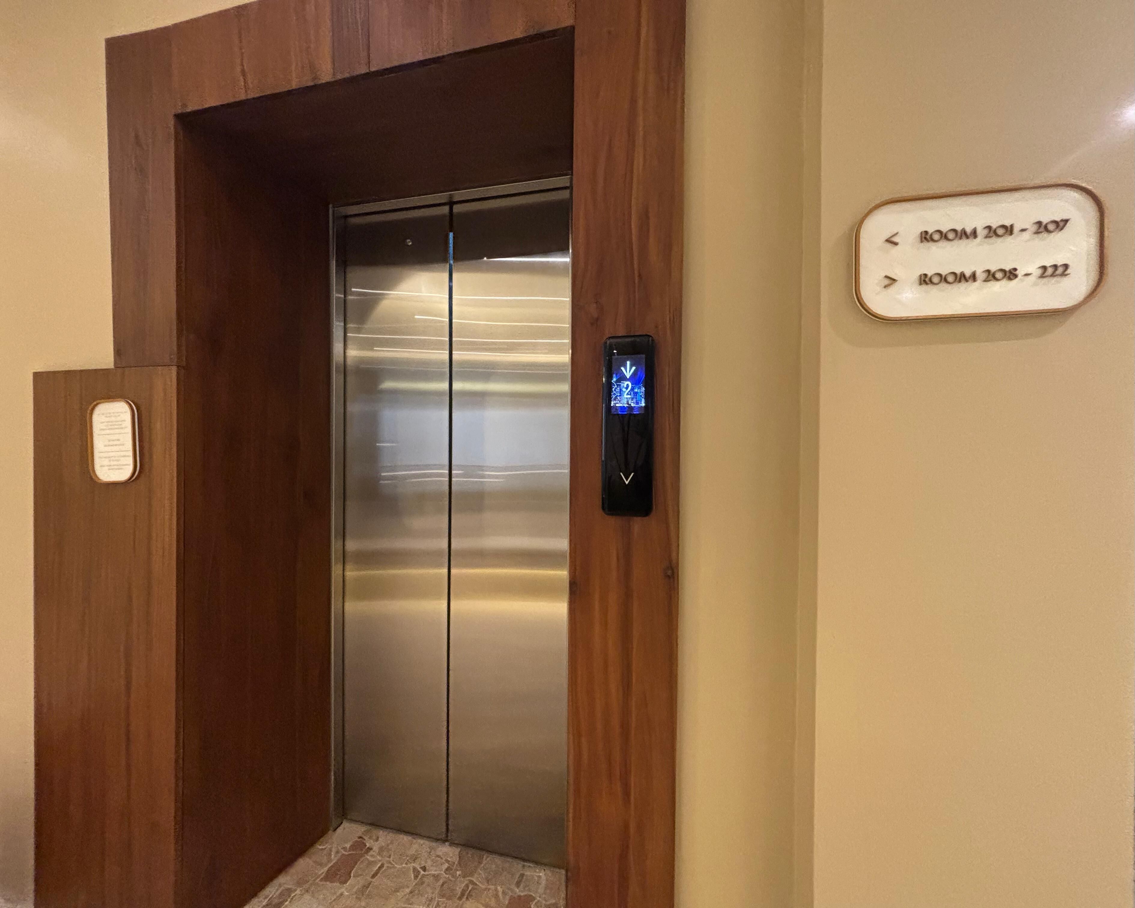 An elevator with a digital display and a sign indicating room numbers 201-207 and 208-222.