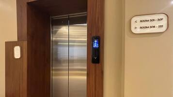 An elevator with a digital display and a sign indicating room numbers 201-207 and 208-222.