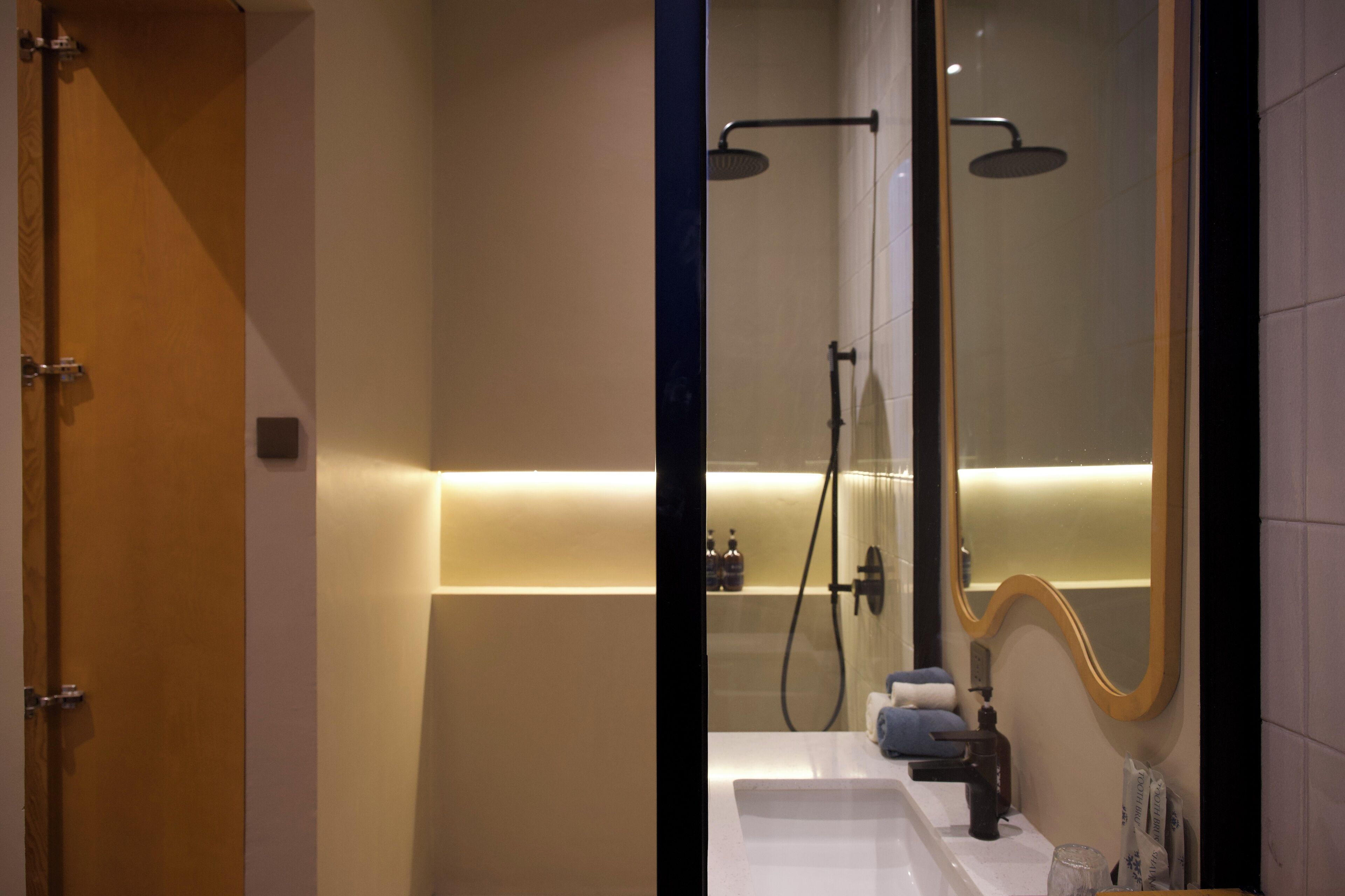 A modern bathroom with a shower, a mirror, and a sink.