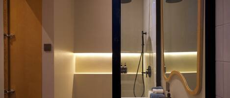 A modern bathroom with a shower, a mirror, and a sink.