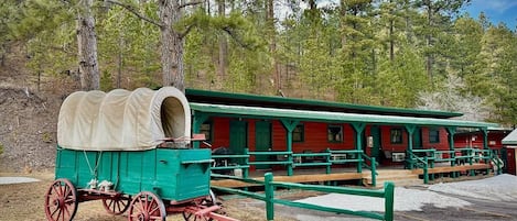 A green covered wagon and a red building with green trim, likely a historical site.