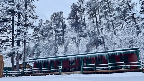 A cabin with a red exterior, green railings, and icicles hanging from the roof.