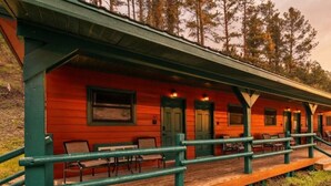 A row of cabins with a wooden deck and green railings.