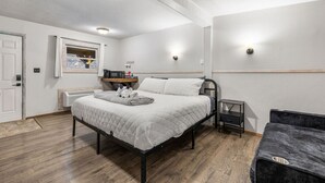 A bedroom with a bed, bedside table, heater, and a small window.
