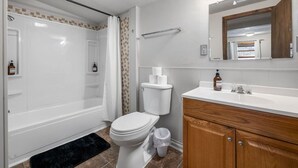 A bathroom with a bathtub, toilet, vanity, and a mirror. - Room 16 – Classic Comfort (Lead)