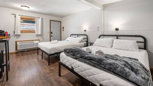 A room with two beds, a desk, a radiator, and a window with a view of a railway track. - Room 16 – Classic Comfort (Lead)