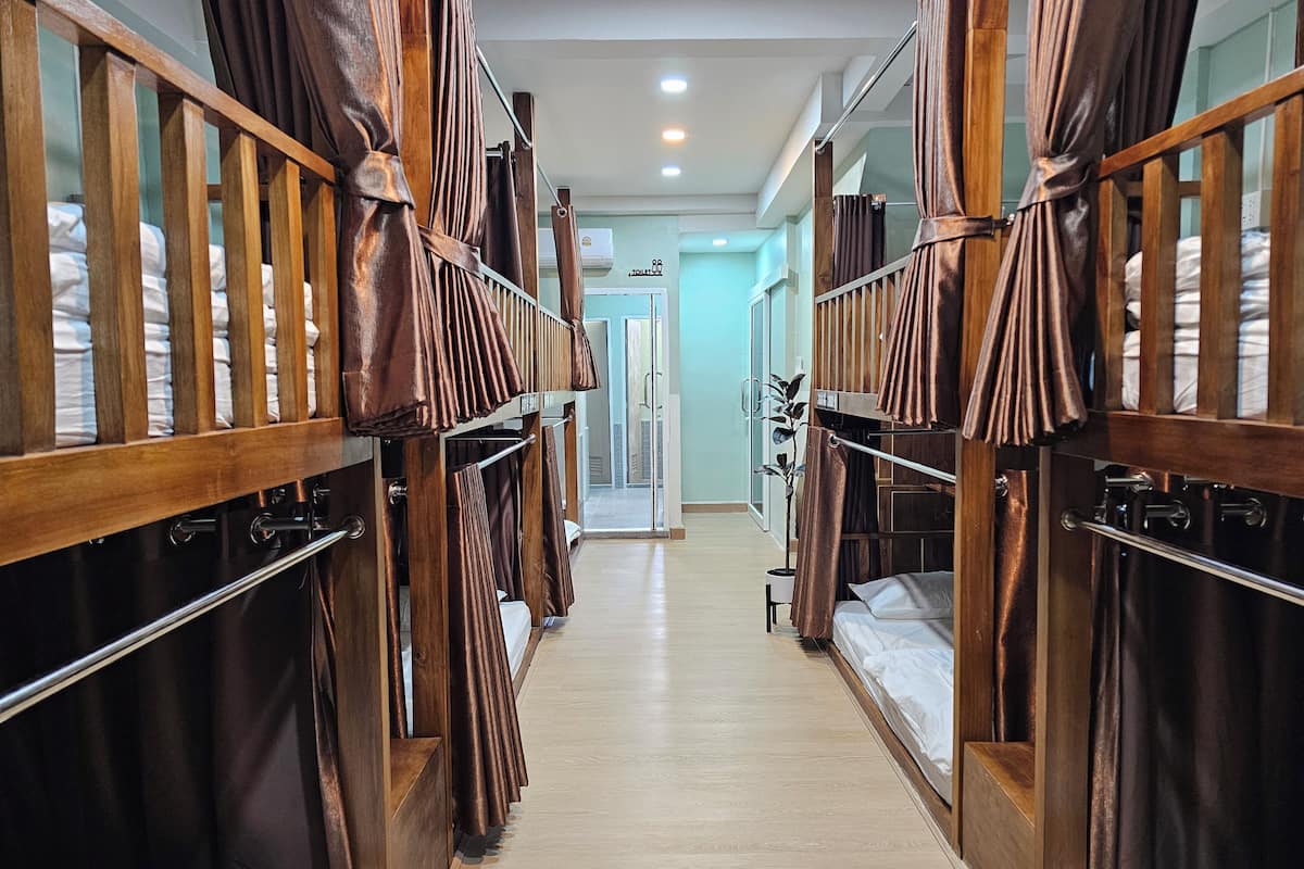 A corridor with bunk beds, wooden railings, and a potted plant.