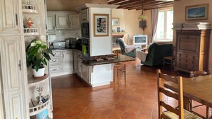 A spacious kitchen with white cabinets, a dining area with a wooden table and chairs, and a living room with a TV and comfortable seating.