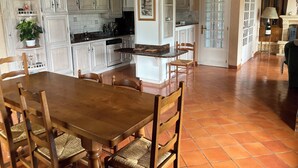 A spacious kitchen with white cabinetry, a wooden dining table, and a tiled floor.