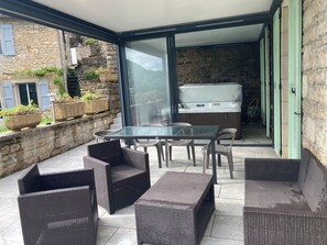 Un patio con mobiliario de mimbre, una mesa de vidrio y un jacuzzi.