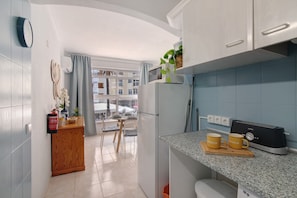 Une cuisine moderne dotée d’un grille-pain encastré, d’un meuble en bois et offrant une vue sur le balcon extérieur.