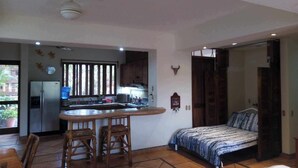 Una habitación funcional con kitchenette, una cama y comedor.