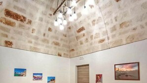 A bedroom with a bed, a red sofa, wooden flooring, a white ceiling with exposed beams, and wall-mounted pictures. - GIONI House (Monopoli)