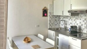 A compact kitchen with white cabinets, a small clock, and a coffee maker. - GIONI House (Monopoli)