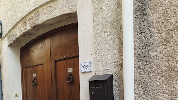 Un edificio con dos puertas de madera, un buzón y un cartel con un número.