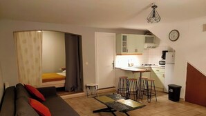 Un espacio habitable pequeño con un sofá, una mesa de comedor pequeña y una kitchenette.
