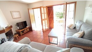 A living room with a sofa, a TV, and a fireplace. There is a sliding glass door leading to an outdoor area. - House with pool on the Costa Dorada, very close to the beach (Sant Salvador)