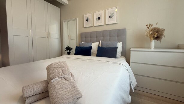 Une chambre à coucher comprenant un lit, une table de chevet, une commode et une armoire.