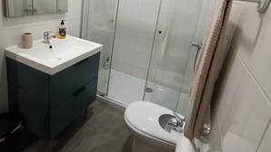 Une salle de bain moderne avec une douche à parois de verre, un lavabo blanc et des toilettes.