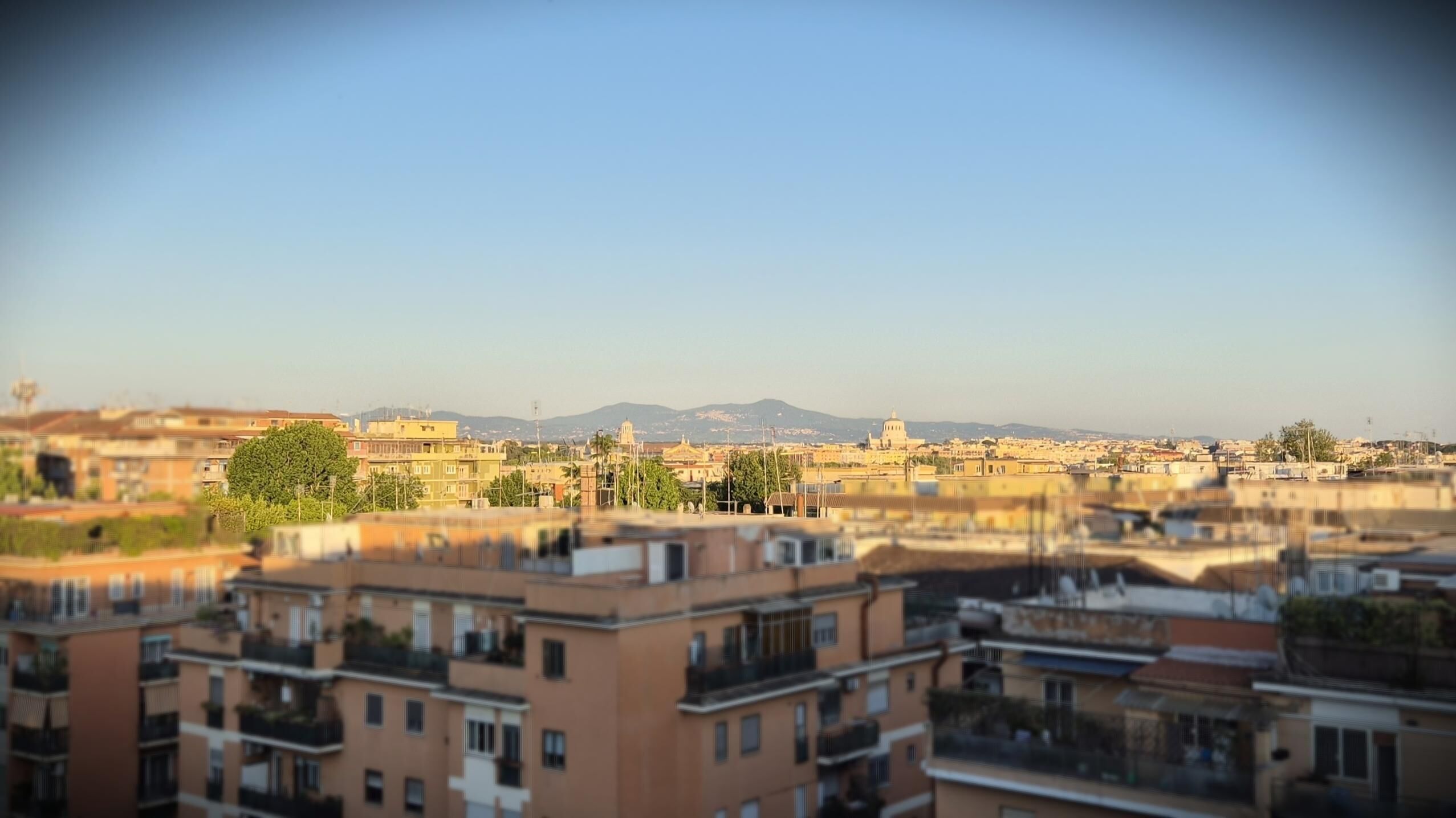 A cityscape with multiple buildings, including residential apartments with balconies and a prominent dome structure in the background.