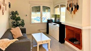 A living room with a sofa, coffee table, fireplace, and a large window with a view of a pool. - Villa on the beach with private pool - holaVivienda Inmobiliaria (Dénia)