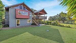 Ein modernes, zweistöckiges Haus mit überdachter Terrasse und gepflegtem Rasen.