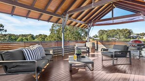 Eine Terrasse mit Holzboden, ein überdachter Bereich mit Holzboden und ein Grill.