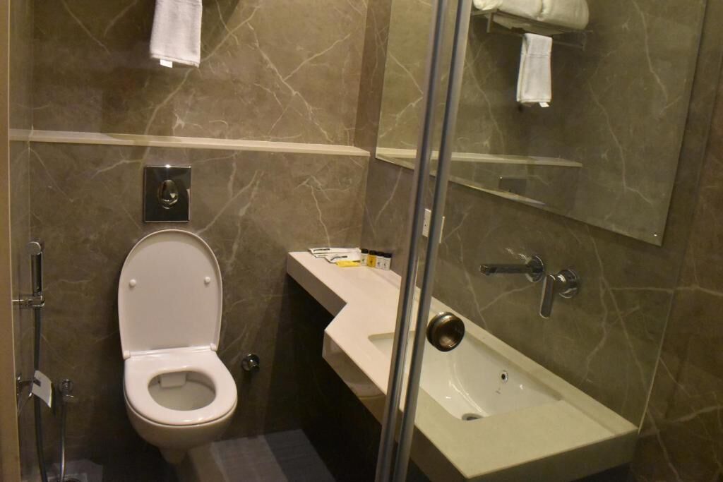 A bathroom with a toilet, sink, and mirror.