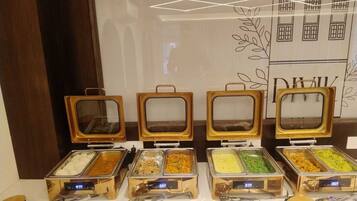 Montaje de bufé con varios recipientes de comida y un reloj digital.
