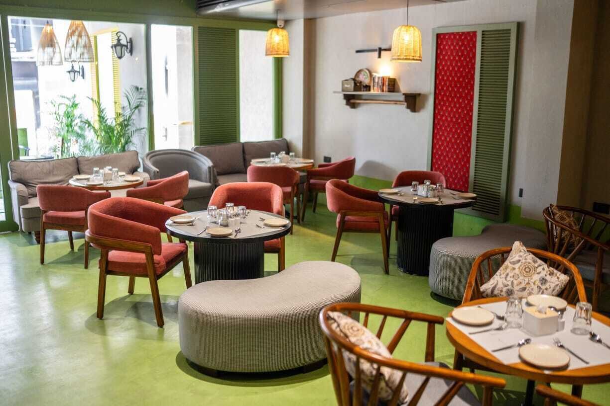 A restaurant with round tables, red chairs, and green walls.
