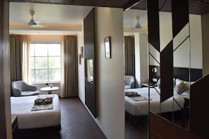 Habitación de hotel con cama, una silla, una mesita y una ventana.