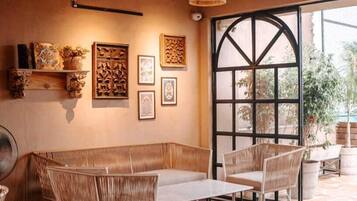 A cozy cafe with wicker furniture, a large window, and artwork on the walls.