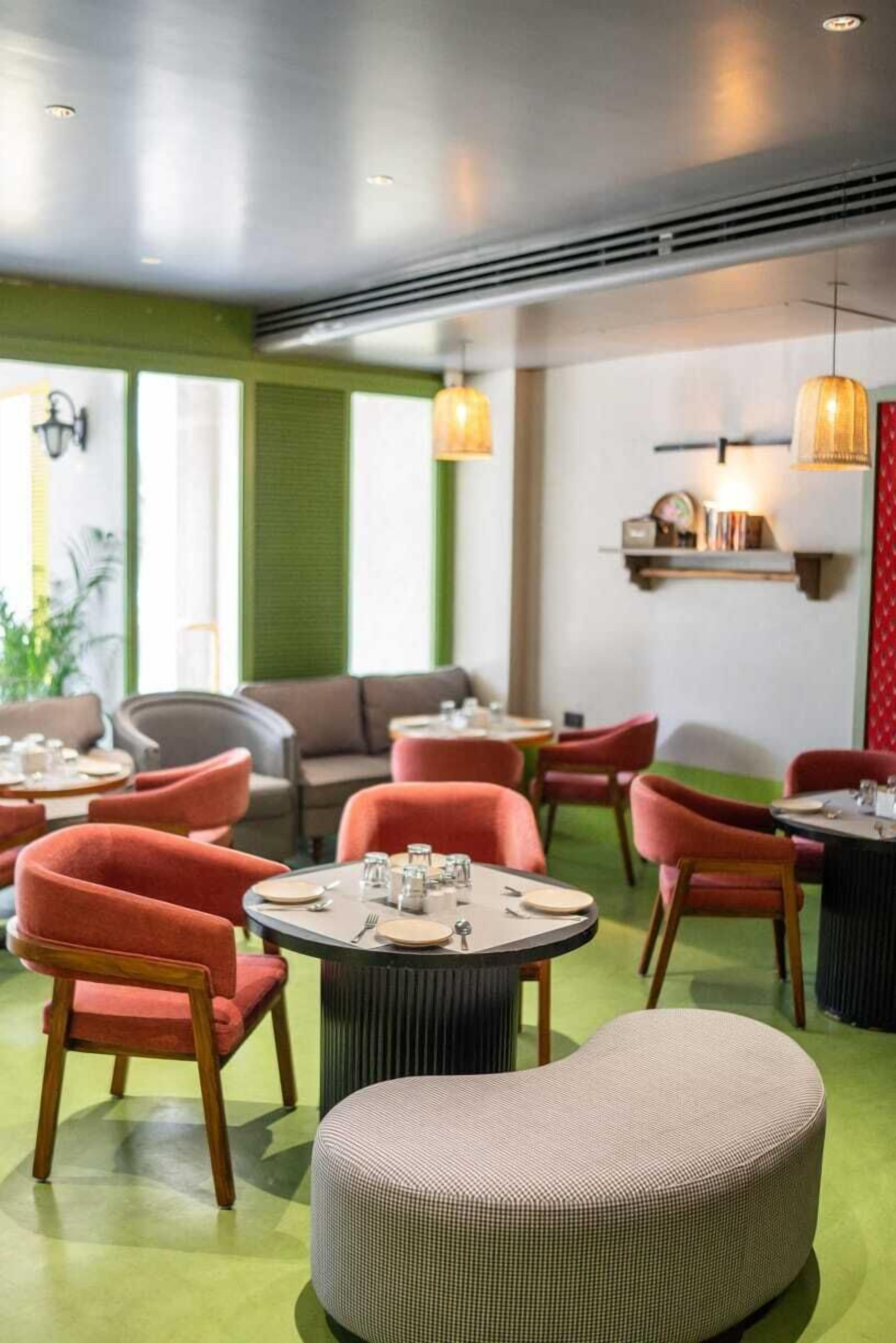 A restaurant with round tables, red upholstered chairs, and a green carpeted floor.
