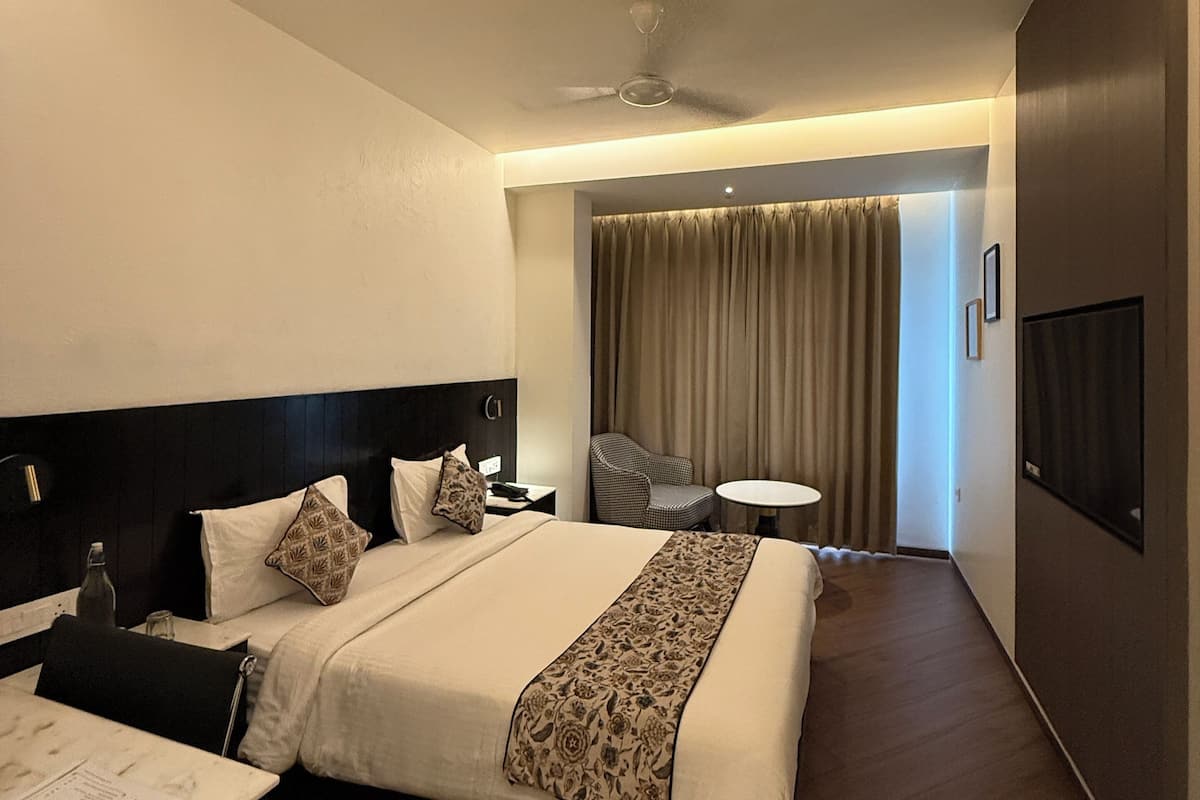 A hotel room with a bed, bedside table, chair, and a small table with a chair.