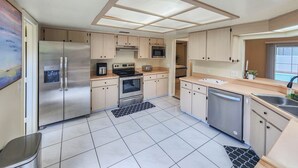 A modern kitchen with stainless steel appliances, light wood cabinets, and a large window. - Solar Heated Pool, Sleeps 10, Peaceful retreat close to shopping and beach! (Palm Coast)